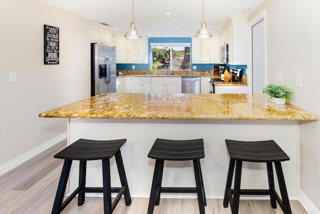 24093 Sargeant Rd, Ramona, CA 92065 - kitchen featuring stainless steel appliances, a peninsula, light stone counters, light wood-style floors, and a breakfast bar