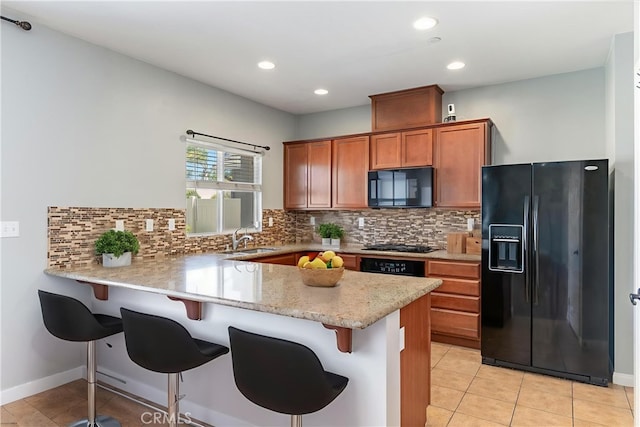 43024 Beamer Ct, Temecula, CA 92592 - kitchen with black appliances, brown cabinetry, a peninsula, a kitchen bar, and tasteful backsplash