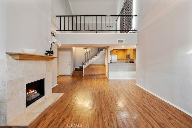 5325 Newcastle Ave Unit 319, Encino, CA 91316 - unfurnished living room with light wood-type flooring, a fireplace, stairs, and a towering ceiling