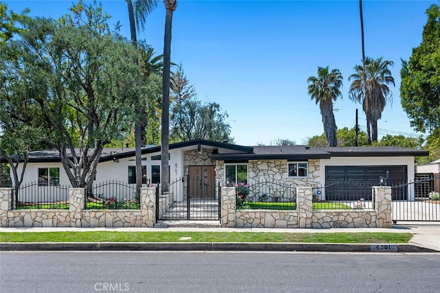 4701 Deseret Dr, Woodland Hills, CA 91364 - mid-century inspired home with stone siding, a fenced front yard, a garage, driveway, and a gate