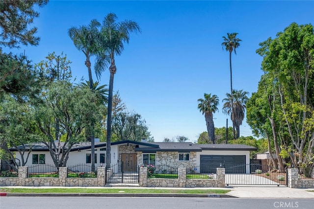 4701 Deseret Dr, Woodland Hills, CA 91364 - view of front of home with an attached garage, a fenced front yard, concrete driveway, stone siding, and a gate