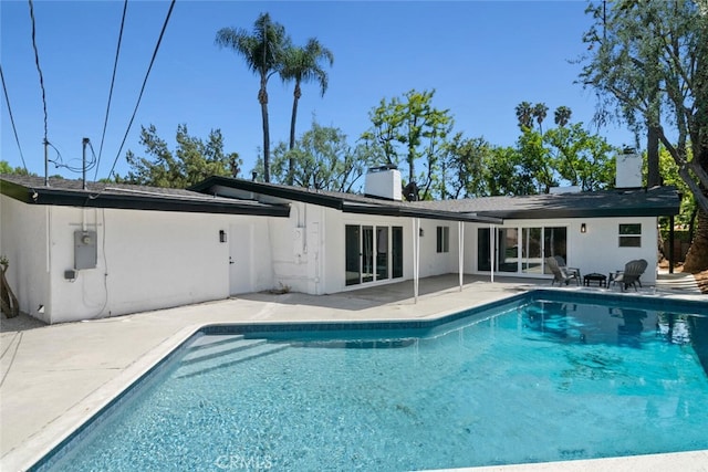 4701 Deseret Dr, Woodland Hills, CA 91364 - rear view of house featuring a chimney, a patio, an outdoor pool, and stucco siding