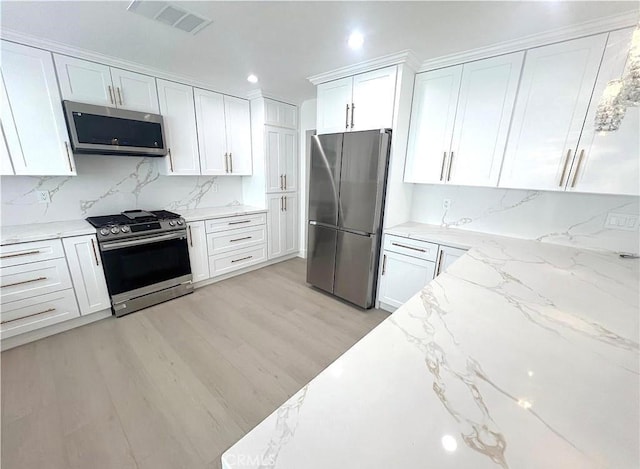 21541 Yucatan Ave, Woodland Hills, CA 91364 - kitchen with stainless steel appliances, white cabinetry, tasteful backsplash, light stone counters, and light wood finished floors