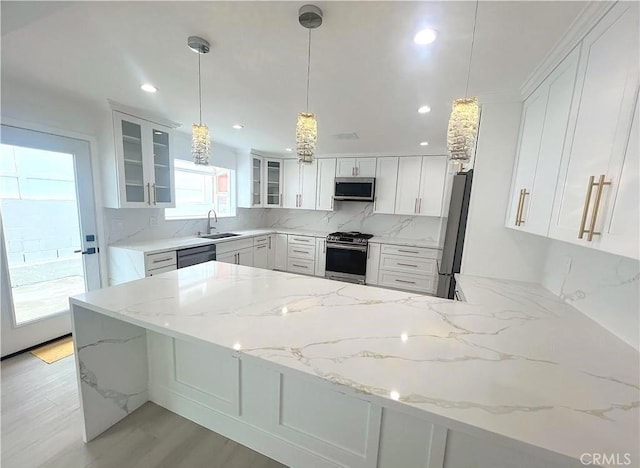 21541 Yucatan Ave, Woodland Hills, CA 91364 - kitchen with stainless steel appliances, a peninsula, decorative backsplash, white cabinetry, and light stone countertops