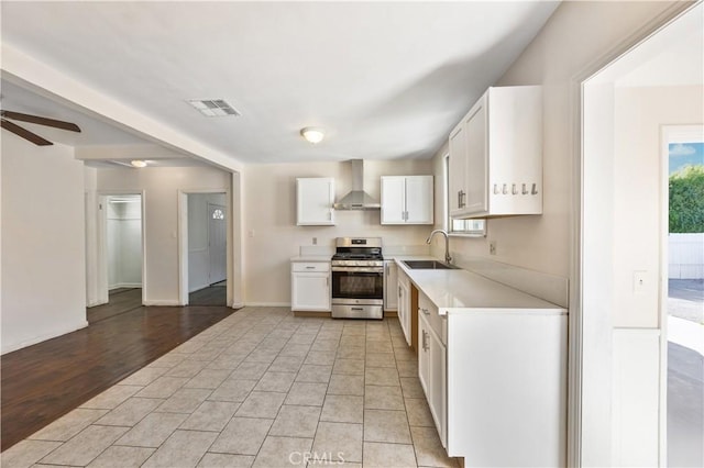 9720 Live Oak Ave, Temple City, CA 91780 - kitchen with stainless steel gas stove, wall chimney range hood, light countertops, white cabinetry, and a ceiling fan