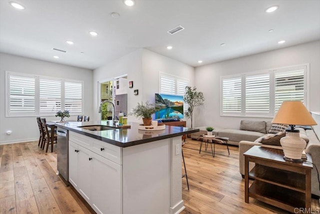 2013 Bravo Loop Unit 2, Chula Vista, CA 91915 - kitchen featuring dishwasher, light wood-style flooring, dark countertops, a kitchen island with sink, and white cabinets