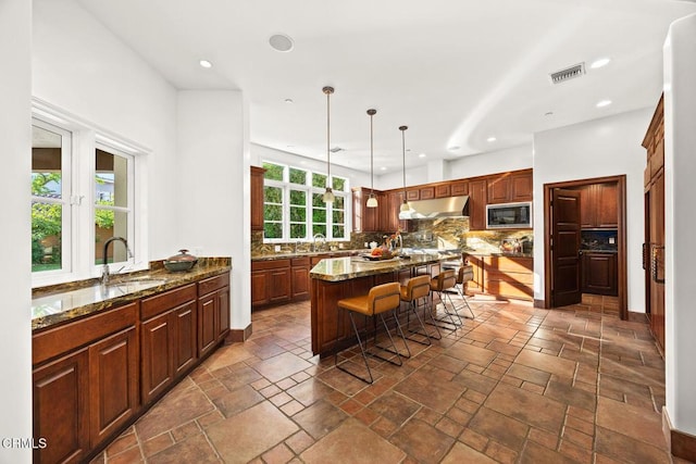 1533 Rancho Ave, Glendale, CA 91201 - kitchen with built in microwave, under cabinet range hood, decorative backsplash, a breakfast bar, and dark stone countertops