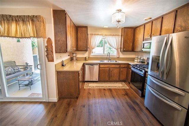 20716 Community St, Winnetka, CA 91306 - kitchen featuring appliances with stainless steel finishes, brown cabinets, light countertops, dark wood-type flooring, and a chandelier
