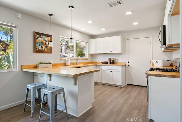 5155 Ardilla Ave, Atascadero, CA 93422 - kitchen with a peninsula, butcher block counters, white cabinets, a breakfast bar, and recessed lighting