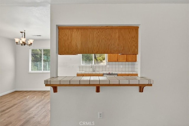 4729 Lookout Mountain Rd, Mariposa, CA 95338 - kitchen with tile countertops, a breakfast bar area, brown cabinets, and light wood-type flooring