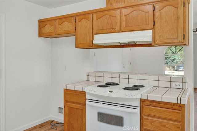 4729 Lookout Mountain Rd, Mariposa, CA 95338 - kitchen featuring electric range, under cabinet range hood, tile countertops, light wood-type flooring, and tasteful backsplash