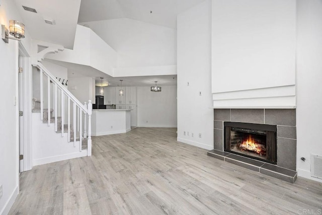 11375 Affinity Ct Unit 206, San Diego, CA 92131 - unfurnished living room featuring a fireplace, wood finished floors, stairs, and lofted ceiling