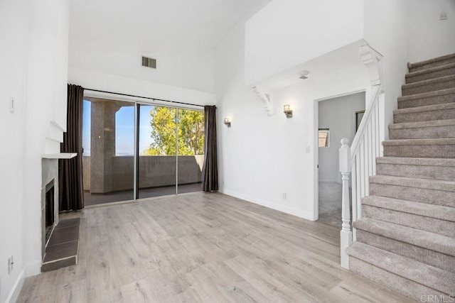 11375 Affinity Ct Unit 206, San Diego, CA 92131 - unfurnished living room with stairway, a towering ceiling, wood finished floors, and a fireplace