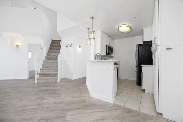 11375 Affinity Ct Unit 206, San Diego, CA 92131 - kitchen featuring stainless steel microwave, white cabinetry, open floor plan, light wood finished floors, and light countertops