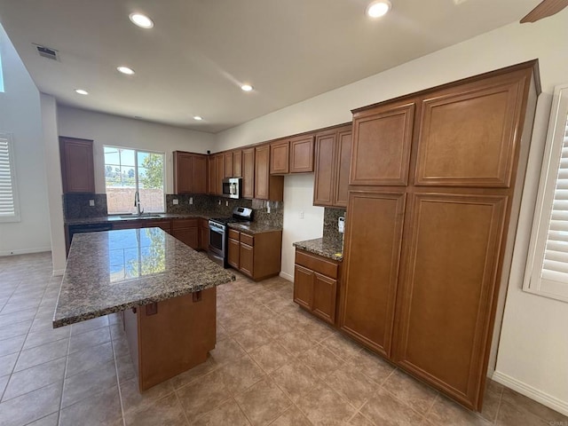 106 Chesapeake Ct, San Marcos, CA 92069 - kitchen featuring appliances with stainless steel finishes, decorative backsplash, a kitchen island, dark stone counters, and recessed lighting