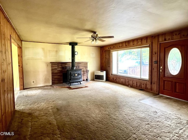 21560 Bald Hill Rd, Fort Bragg, CA 95437 - unfurnished living room with a wood stove, heating unit, ceiling fan, carpet floors, and wooden walls