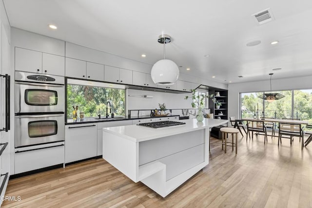453 Frontenac Ave, Los Angeles, CA 90065 - kitchen with stainless steel appliances, white cabinetry, a center island, recessed lighting, and light wood-style flooring