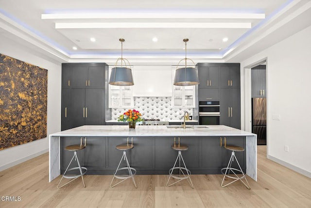 4828 Oakwood Ave, La Canada Flintridge, CA 91011 - kitchen with a raised ceiling, double oven, backsplash, and light wood-style flooring