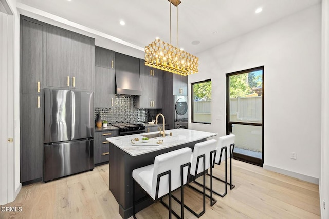 4828 Oakwood Ave, La Canada Flintridge, CA 91011 - kitchen with freestanding refrigerator, wall chimney range hood, stacked washer / drying machine, gas stove, and a kitchen island with sink