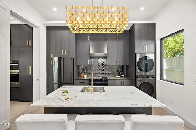 4828 Oakwood Ave, La Canada Flintridge, CA 91011 - kitchen featuring stacked washer / drying machine, appliances with stainless steel finishes, light wood-style flooring, extractor fan, and backsplash