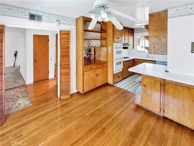 11753 Kling St, Valley Village, CA 91607 - kitchen featuring light wood finished floors, light countertops, white double oven, a ceiling fan, and under cabinet range hood