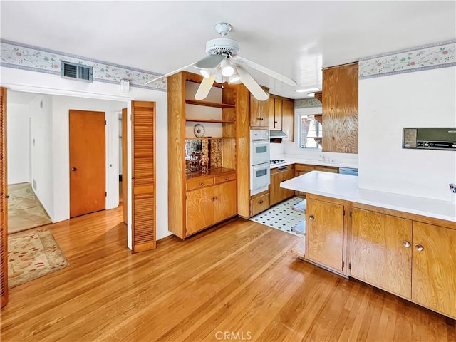 11753 Kling St, Valley Village, CA 91607 - kitchen featuring light wood-type flooring, light countertops, double oven, a ceiling fan, and a peninsula