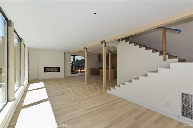 216 Leonard Ln, Big Bear, CA 92386 - unfurnished living room with light wood-style flooring, a glass covered fireplace, and stairs