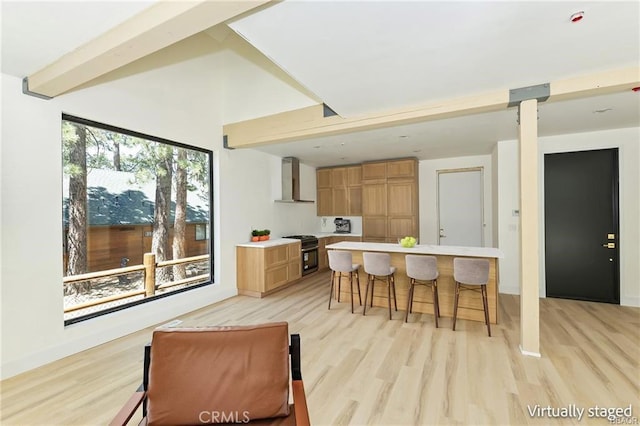 216 Leonard Ln, Big Bear, CA 92386 - kitchen featuring wall chimney range hood, gas range, light wood-style flooring, a breakfast bar area, and light countertops