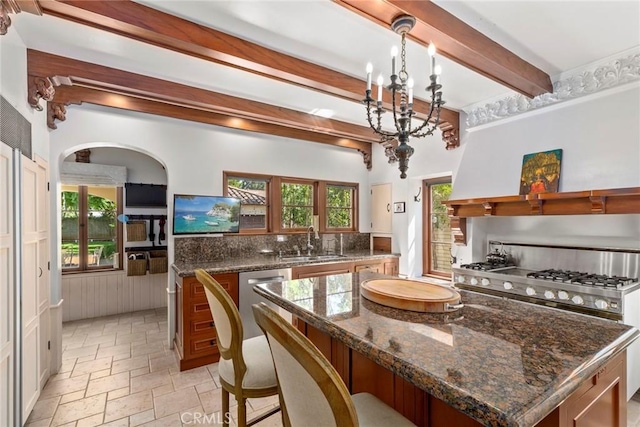 1811 N Flower St, Santa Ana, CA 92706 - kitchen featuring beamed ceiling, stone tile flooring, a chandelier, arched walkways, and appliances with stainless steel finishes