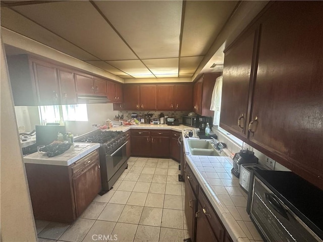 1409 E 41st Pl, Los Angeles, CA 90011 - kitchen with high end stove, tile counters, light tile patterned floors, and under cabinet range hood