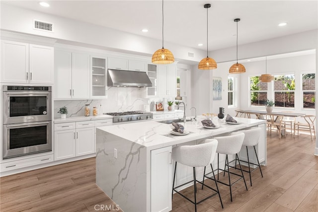 13428 Silver Sky Rd, Rancho Cucamonga, CA 91739 - kitchen featuring stainless steel appliances, under cabinet range hood, white cabinetry, light wood-style flooring, and recessed lighting