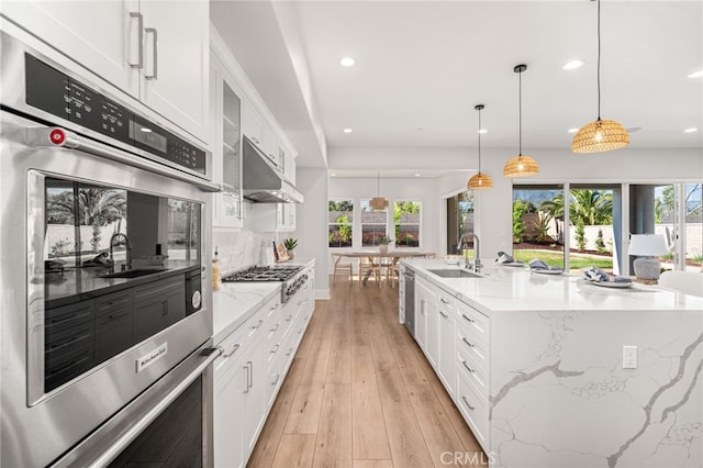 13428 Silver Sky Rd, Rancho Cucamonga, CA 91739 - kitchen with appliances with stainless steel finishes, recessed lighting, white cabinetry, under cabinet range hood, and light wood-style floors
