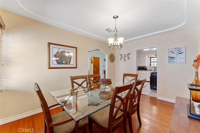 2118 W 84th St, Los Angeles, CA 90047 - dining space featuring arched walkways, light wood finished floors, and a chandelier