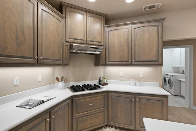7105 Rayar Rd, Atascadero, CA 93422 - kitchen with gas stovetop, washing machine and clothes dryer, light countertops, under cabinet range hood, and light carpet