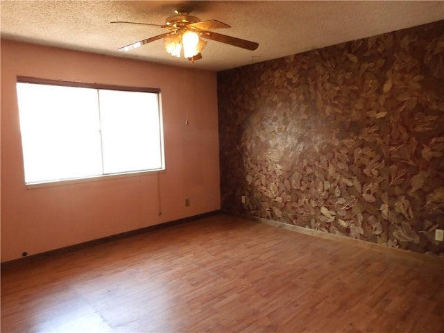 17216 Cedar Way, Clearlake Oaks, CA 95423 - spare room featuring wood finished floors, a ceiling fan, a textured ceiling, and wallpapered walls