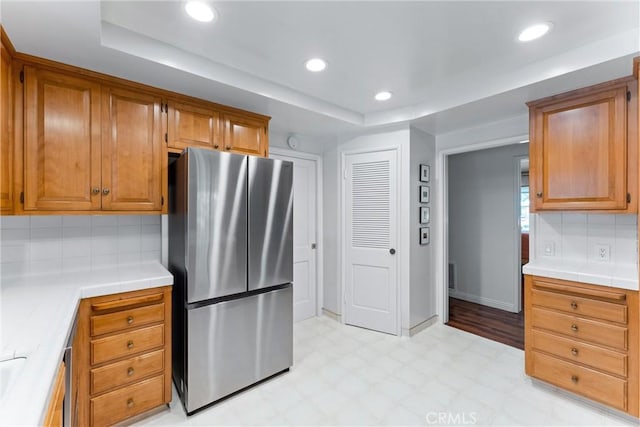 2117 N Westwood Ave, Santa Ana, CA 92706 - kitchen with freestanding refrigerator, light floors, a raised ceiling, decorative backsplash, and brown cabinetry