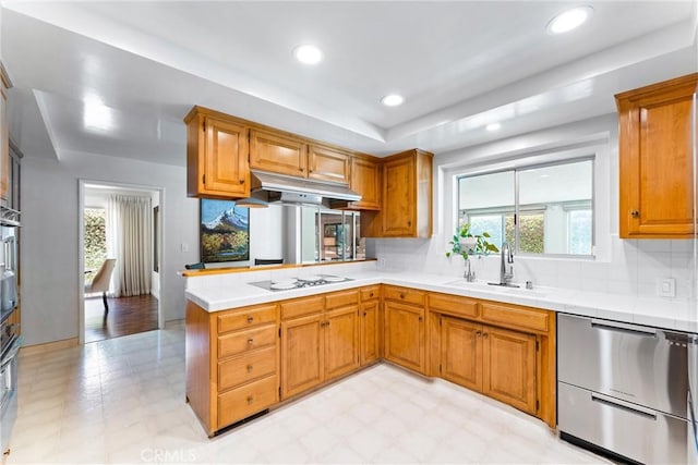 2117 N Westwood Ave, Santa Ana, CA 92706 - kitchen with stainless steel dishwasher, under cabinet range hood, white cooktop, light floors, and backsplash