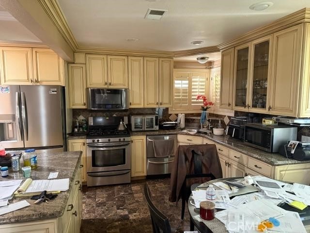 830 W Heber St, Glendora, CA 91741 - kitchen featuring appliances with stainless steel finishes, cream cabinetry, glass insert cabinets, and dark stone countertops