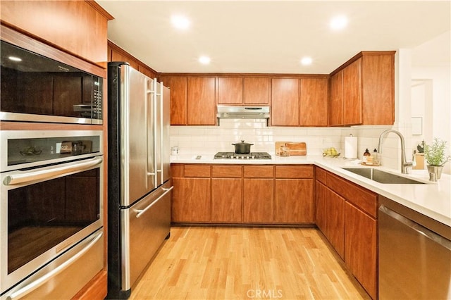10601 Eton Ave, Chatsworth, CA 91311 - kitchen featuring appliances with stainless steel finishes, under cabinet range hood, light wood-style floors, light countertops, and brown cabinets