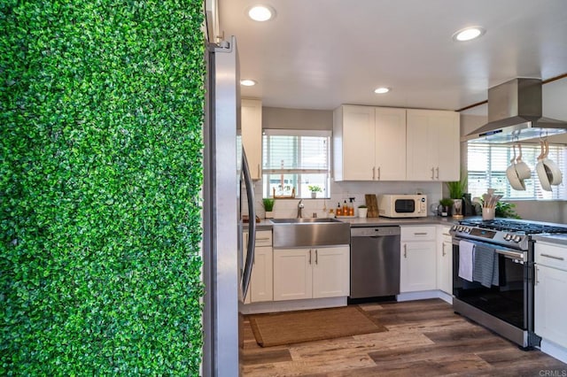 3721 Chamoune Ave, San Diego, CA 92105 - kitchen featuring appliances with stainless steel finishes, wall chimney exhaust hood, white cabinetry, dark wood finished floors, and recessed lighting