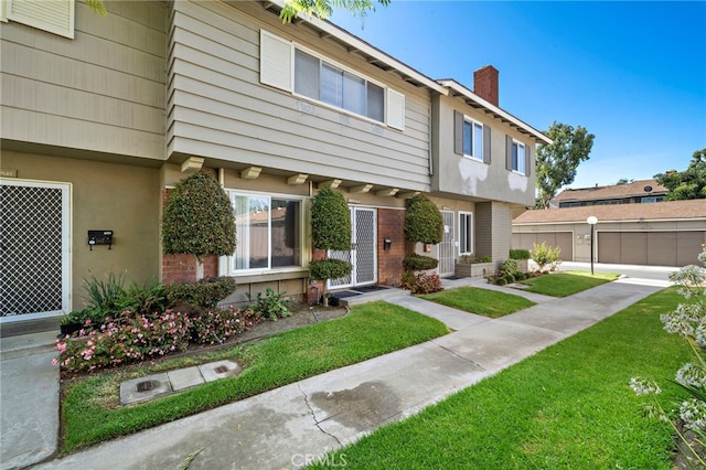 11903 Oertly Cir, Garden Grove, CA 92840 - colonial-style house featuring a chimney, a front yard, stucco siding, and brick siding