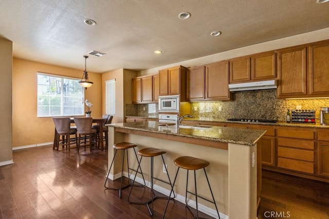 53085 Memorial St, Lake Elsinore, CA 92532 - kitchen with built in microwave, under cabinet range hood, brown cabinets, a textured ceiling, and recessed lighting