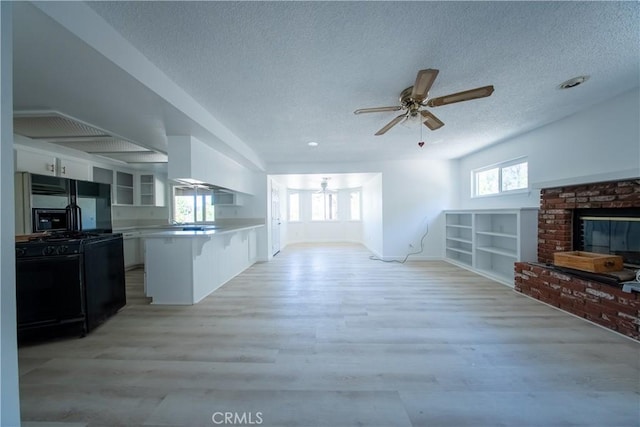 16520 Adelia St, Hesperia, CA 92345 - unfurnished living room featuring a textured ceiling, ceiling fan, light wood finished floors, and a brick fireplace