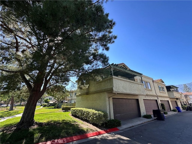 8426 Western Trail Pl Unit E, Rancho Cucamonga, CA 91730 - view of home's exterior featuring stucco siding, an attached garage, and a yard