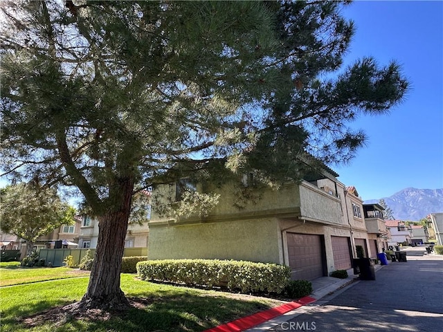 8426 Western Trail Pl Unit E, Rancho Cucamonga, CA 91730 - view of property exterior featuring an attached garage, a residential view, a mountain view, stucco siding, and a lawn
