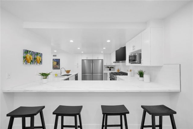 5042 Olympic Dr, Los Alamitos, CA 90720 - kitchen with stainless steel appliances, a peninsula, light stone counters, and recessed lighting