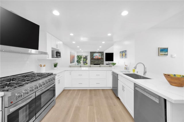 5042 Olympic Dr, Los Alamitos, CA 90720 - kitchen featuring appliances with stainless steel finishes, a peninsula, light wood finished floors, white cabinets, and recessed lighting