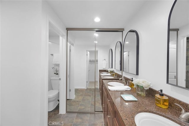 5042 Olympic Dr, Los Alamitos, CA 90720 - bathroom with double vanity, stone finish floors, recessed lighting, and a walk in closet