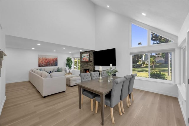 5042 Olympic Dr, Los Alamitos, CA 90720 - dining space featuring a stone fireplace, light wood-style floors, high vaulted ceiling, and recessed lighting