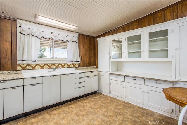 559 Edgar Ave Unit A2-282, Beaumont, CA 92223 - kitchen with white cabinets, glass insert cabinets, light floors, and wood walls